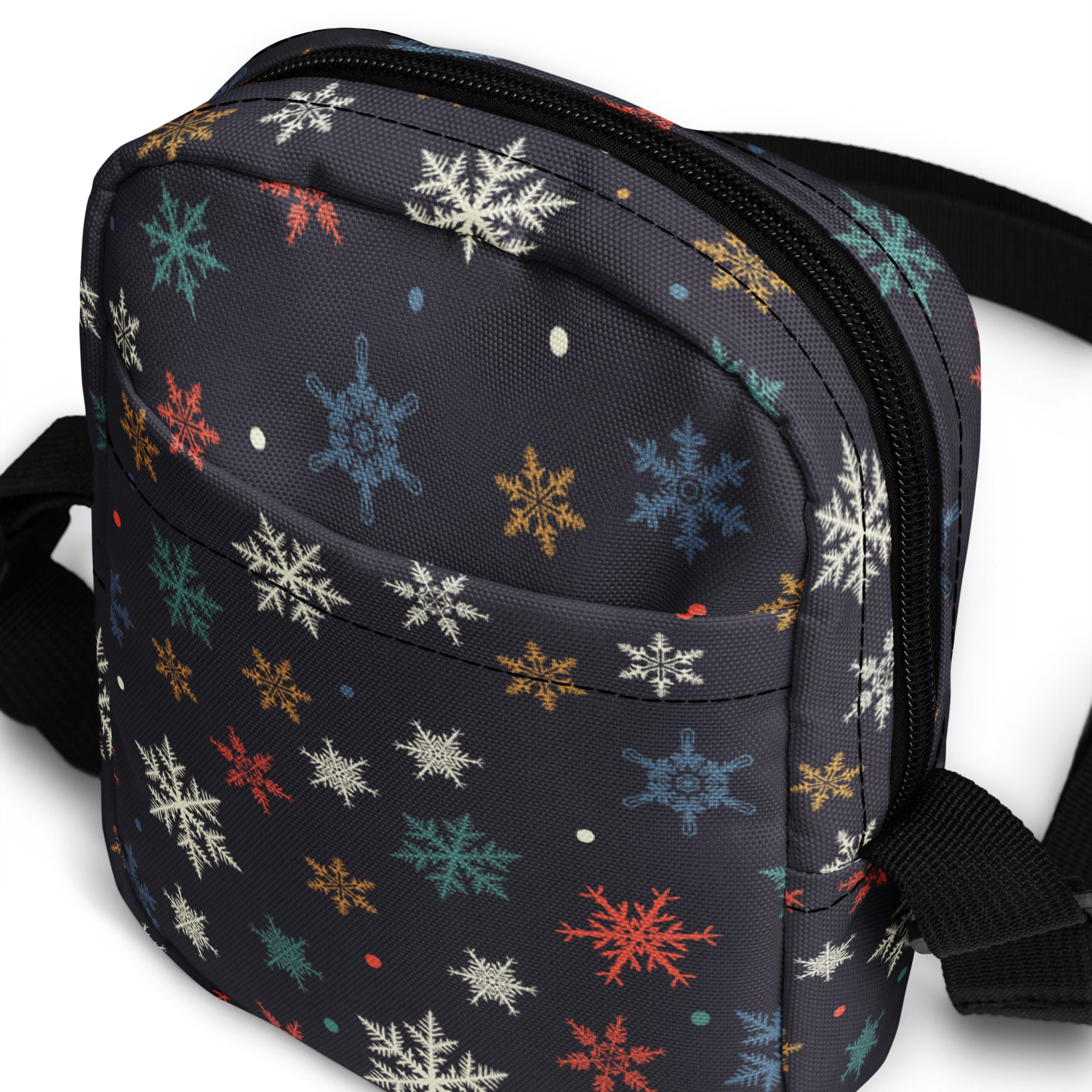 A dark gray crossbody purse with a colorful snowflake pattern in white red blue and gold for women