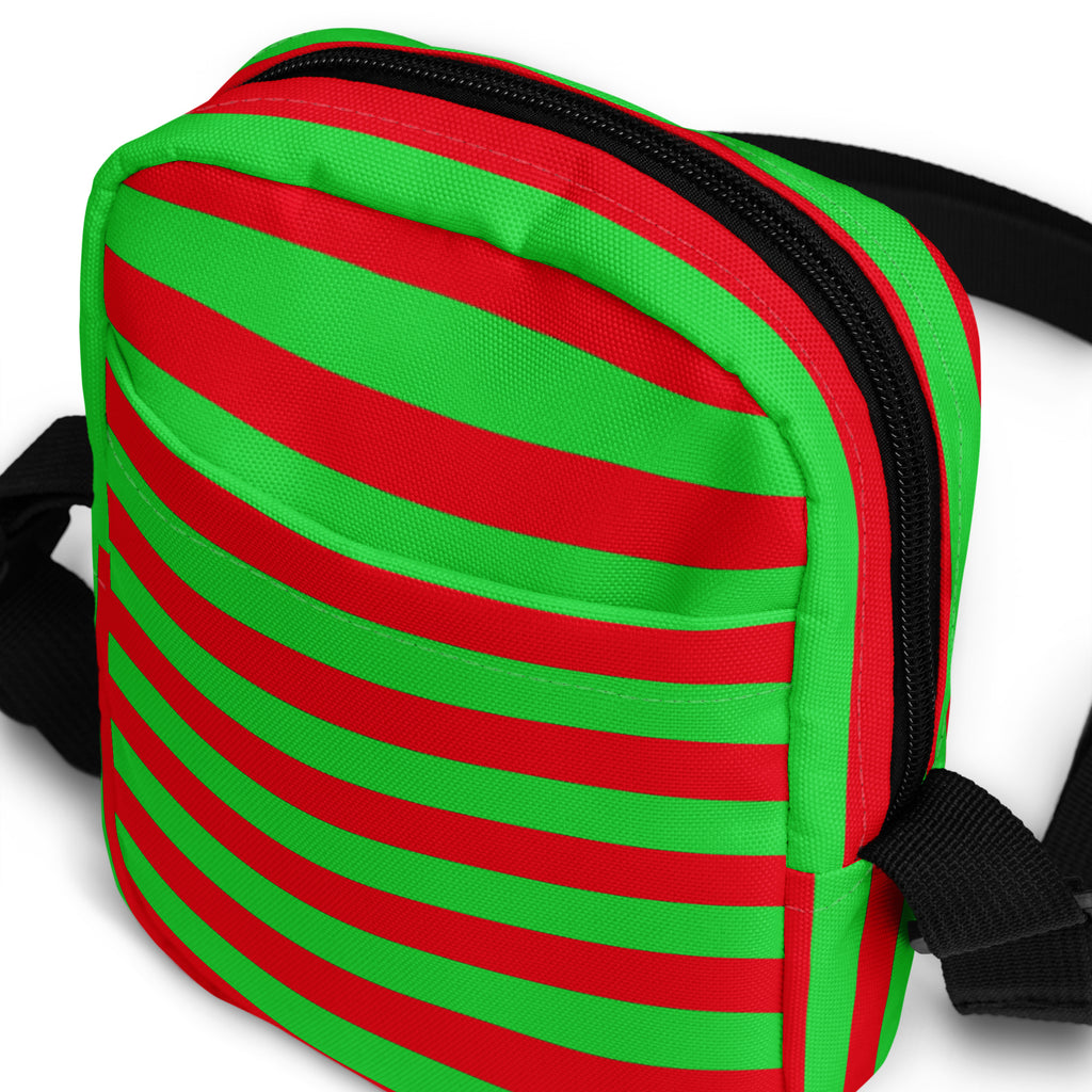 A vibrant red and green striped canvas crossbody purse with black zipper and straps for Christmas use