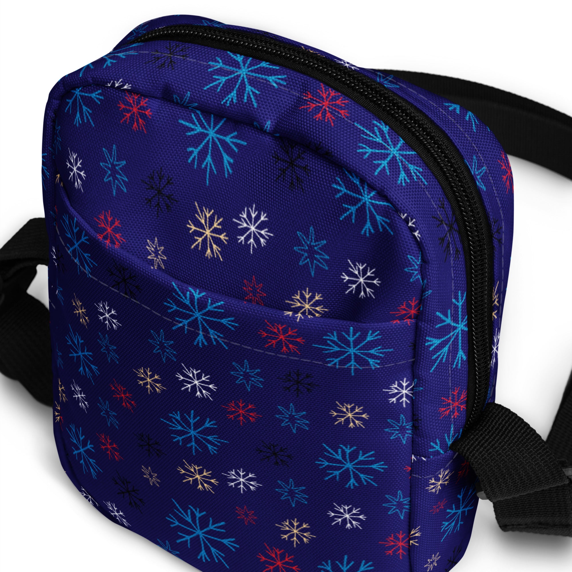 A navy blue girls crossbody purse with a vibrant multicolor snowflake pattern in red white teal and gold