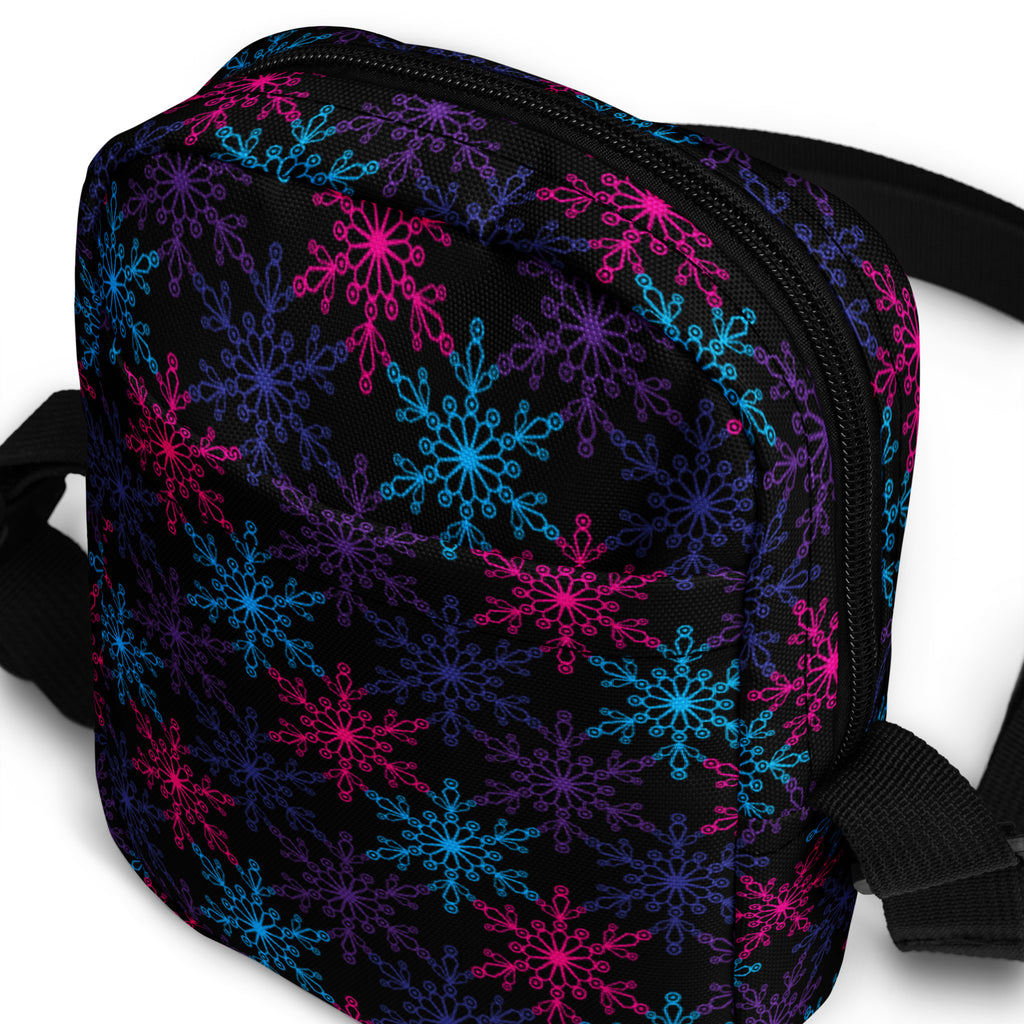 A black crossbody purse with neon pink blue and purple snowflake pattern for girls