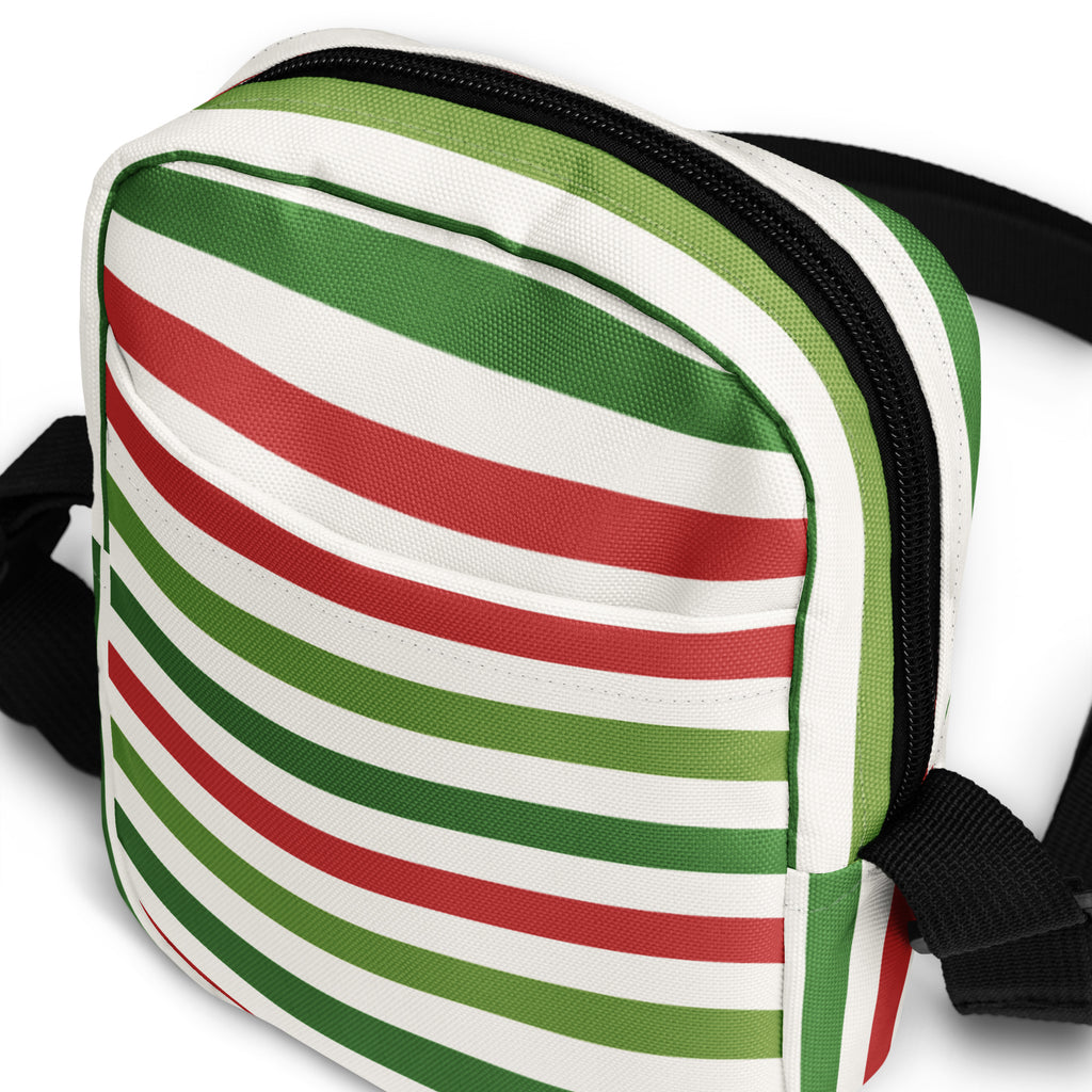 A christmas striped women’s crossbody purse with bold green red and white diagonal stripes on canvas fabric with black zippers