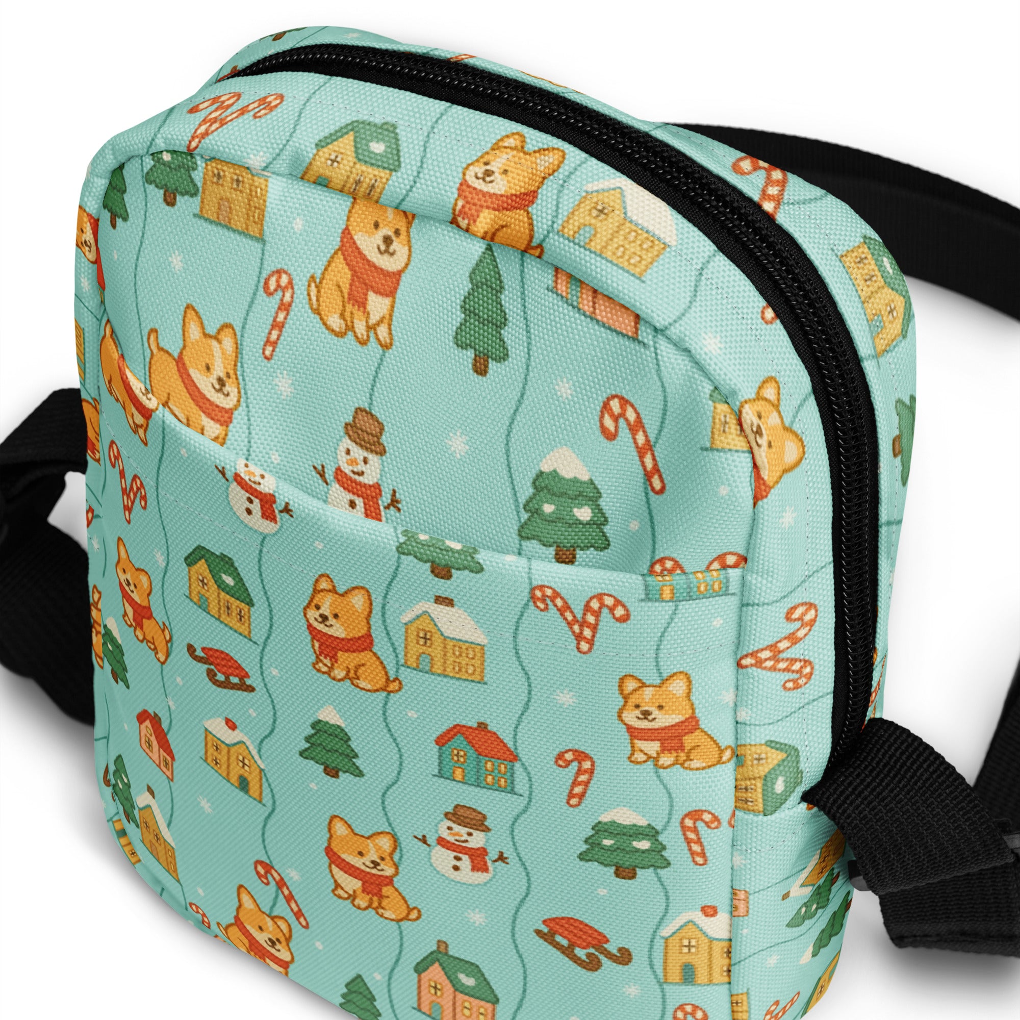 A light blue fabric crossbody bag with festive cartoon corgis candy canes snowmen and Christmas houses pattern