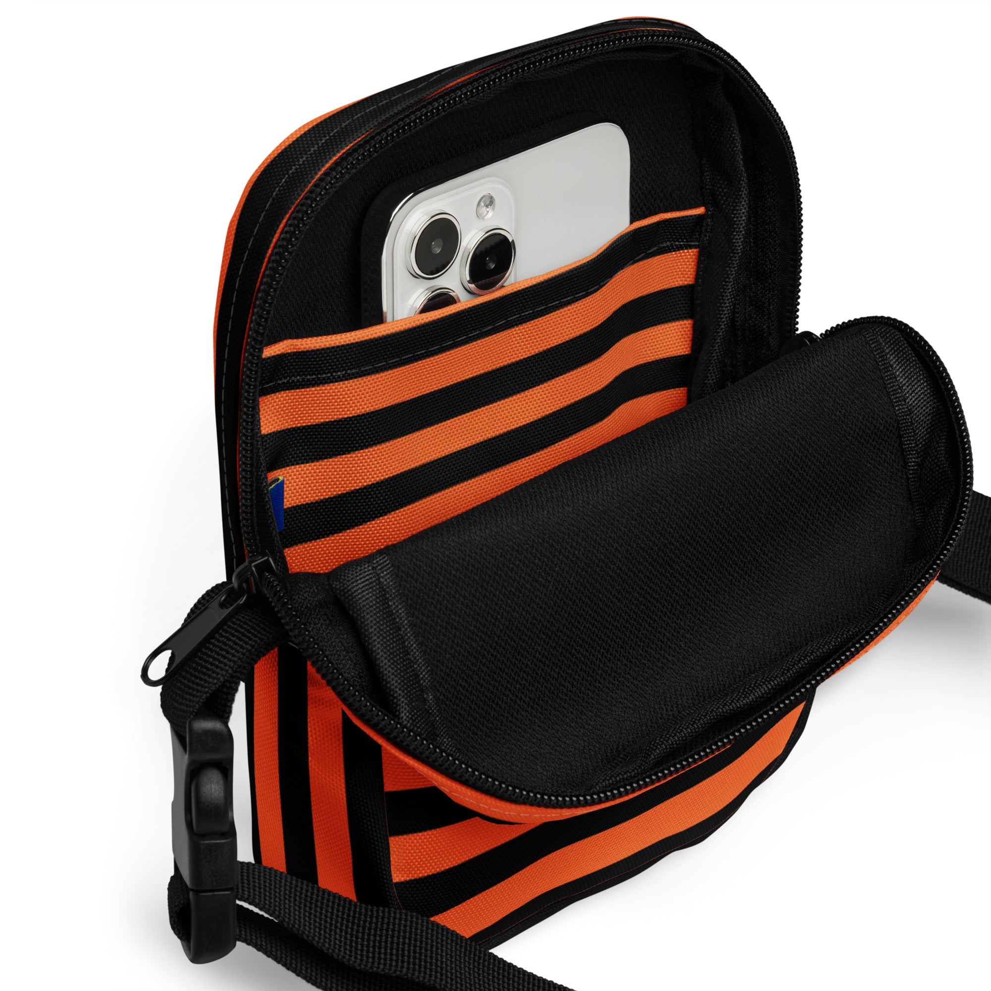 Girls orange and black striped Halloween crossbody purse with zippered compartment holding a smartphone