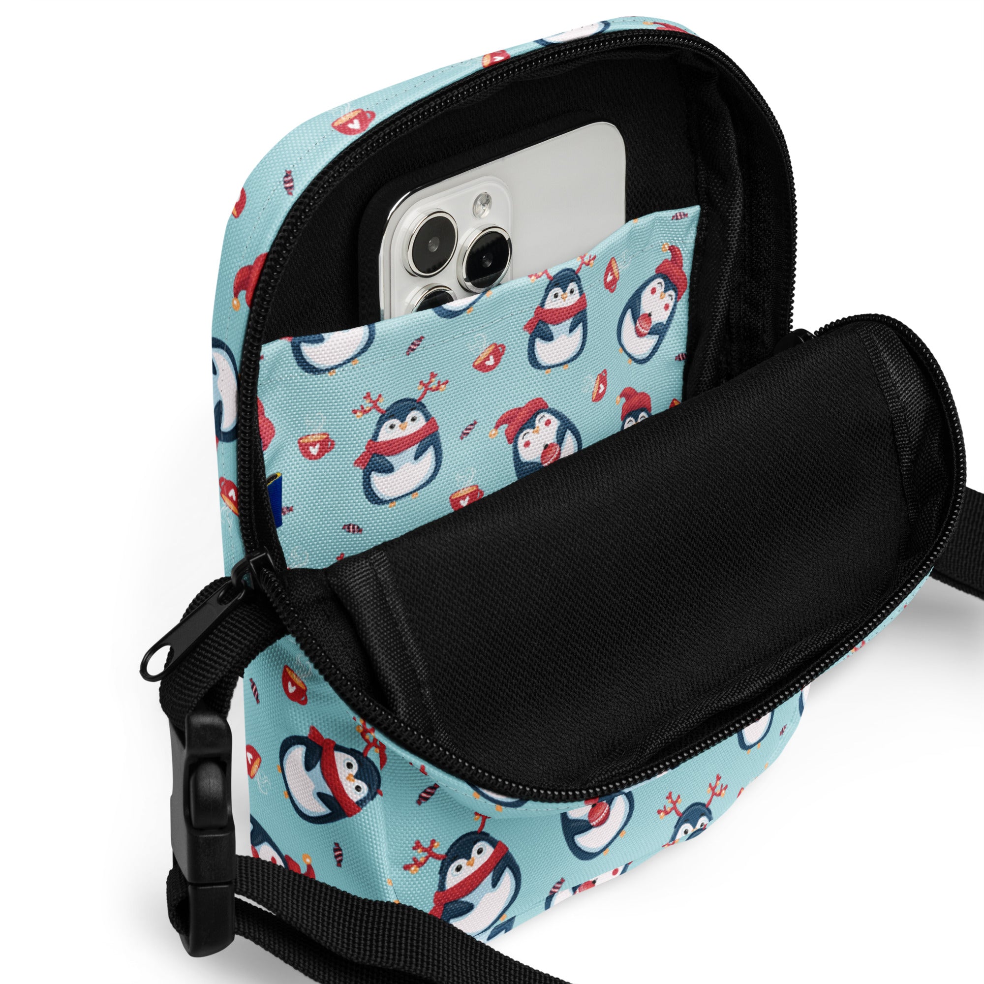 A light blue girls reindeer penguin crossbody purse with cartoon penguins wearing red scarves and black straps and zippers