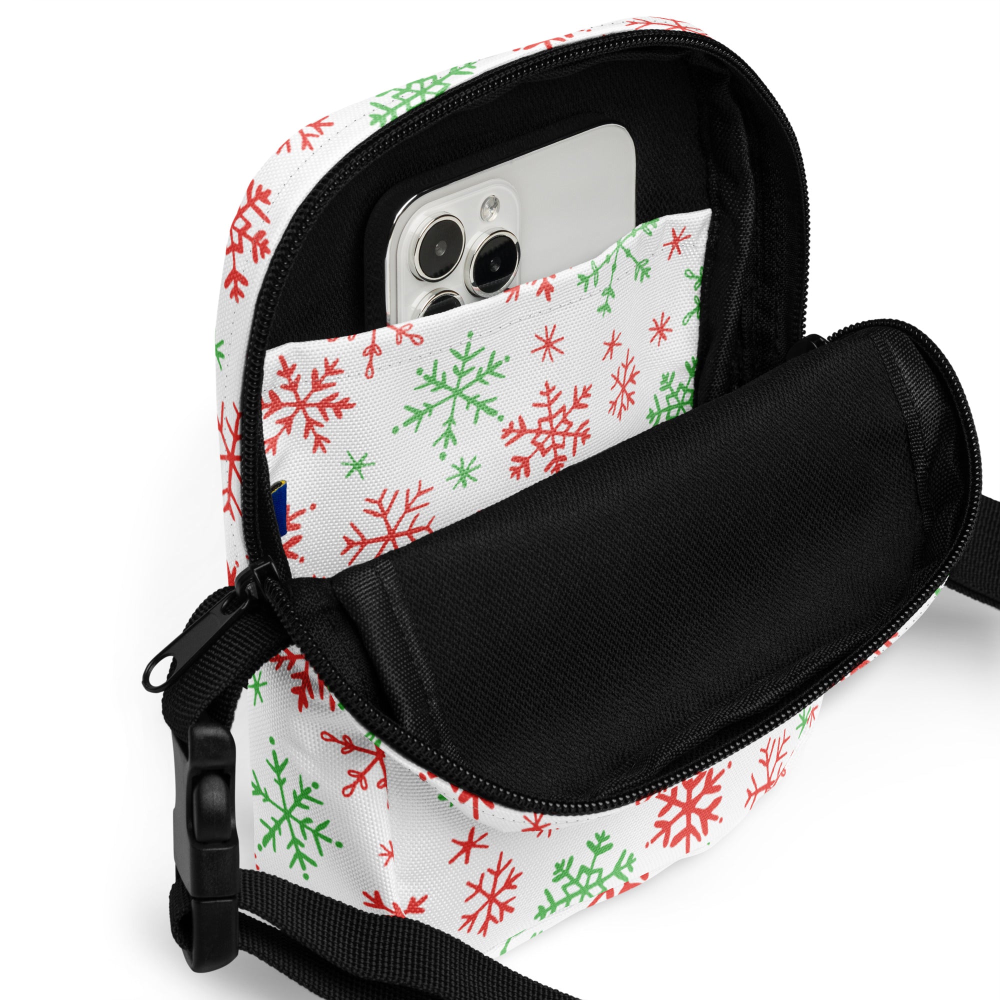 White crossbody bag with red and green snowflake pattern, black zipper trim, and adjustable strap for christmas use