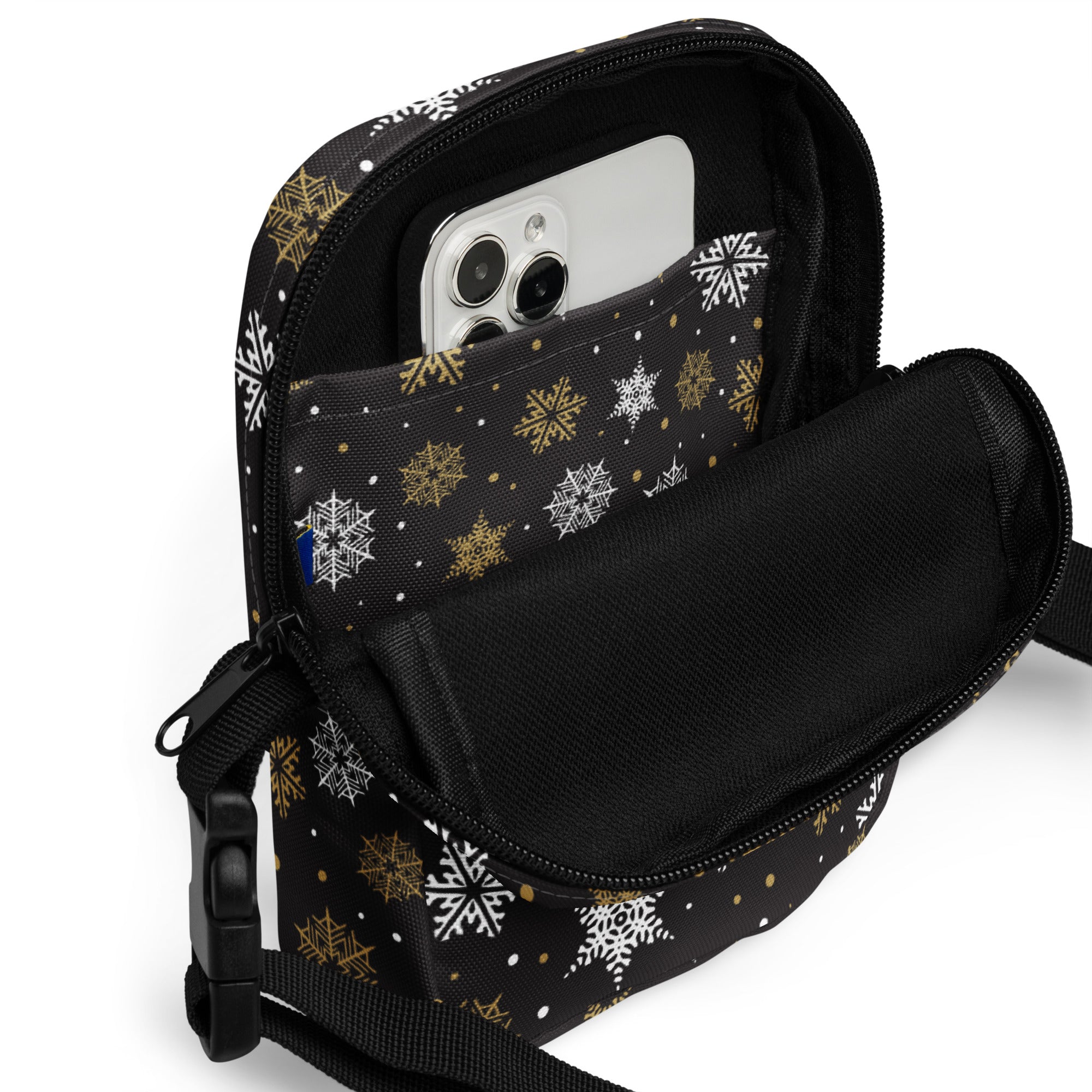Girls black and gold snowflakes crossbody purse with festive pattern and interior pocket holding a smartphone