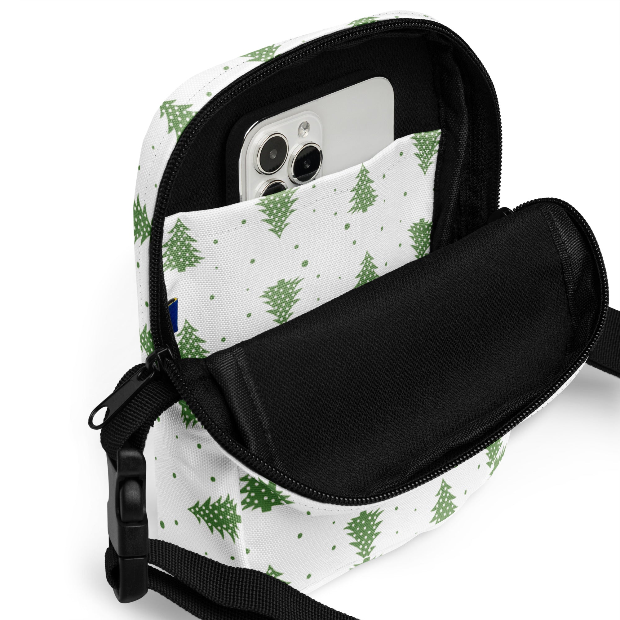 White crossbody bag with green pine tree pattern and black zipper accents for christmas winter use