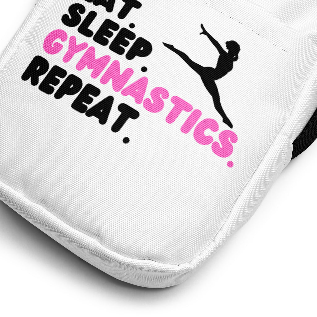 White canvas crossbody bag with black and pink embroidered eat sleep gymnastics repeat design and gymnast silhouette