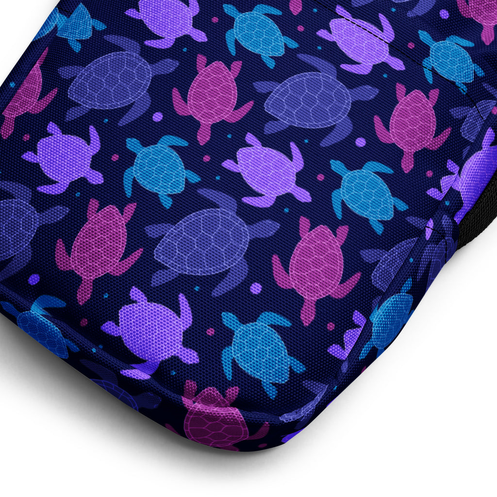 Navy blue girls crossbody purse with vibrant purple pink and teal sea turtle pattern on the front cushion side