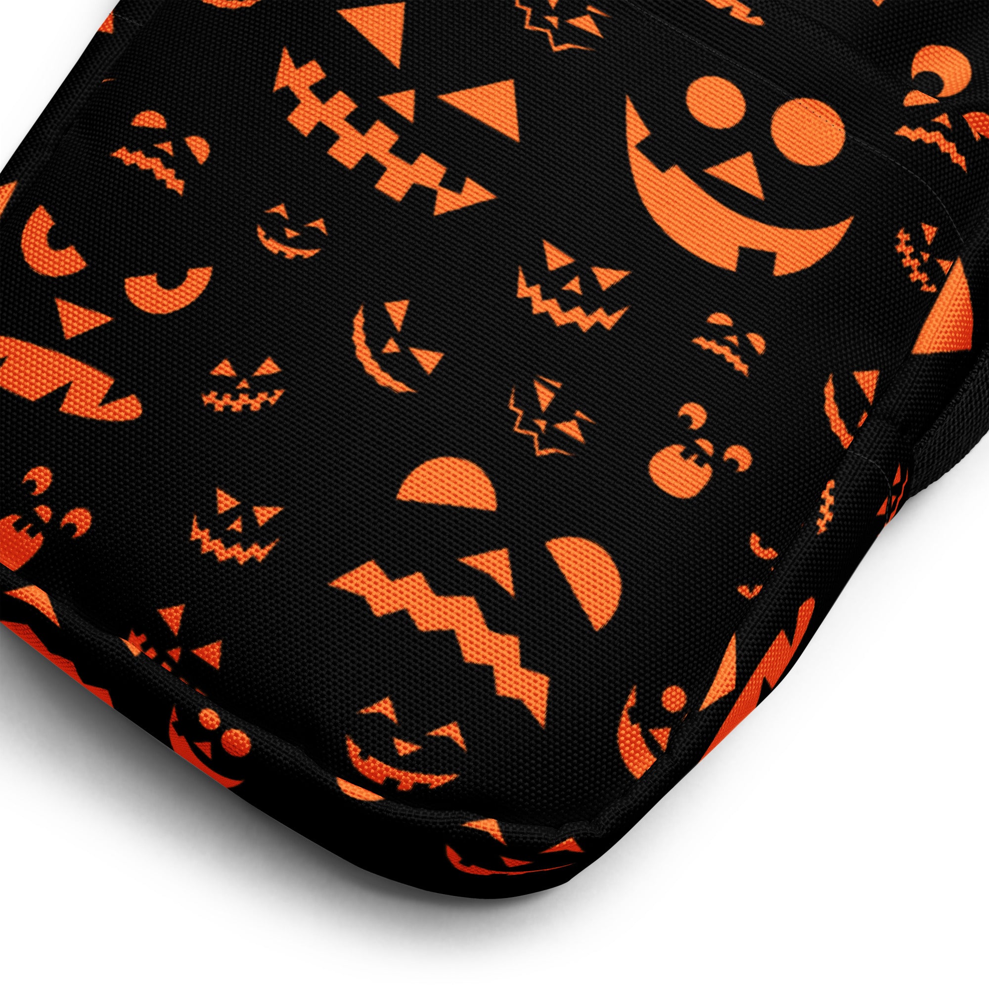 Black fabric pouch crossbody purse decorated with orange jack-o-lantern faces in various sizes and expressions