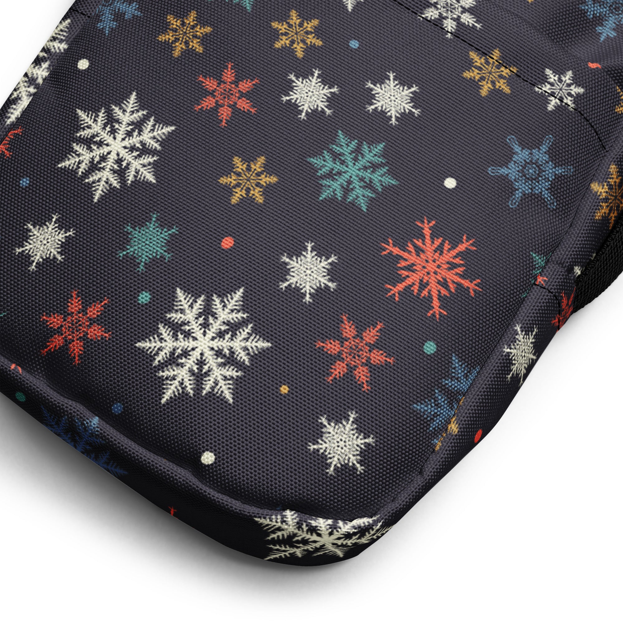 A black fabric crossbody purse with colorful snowflakes in white red gold and teal festive pattern