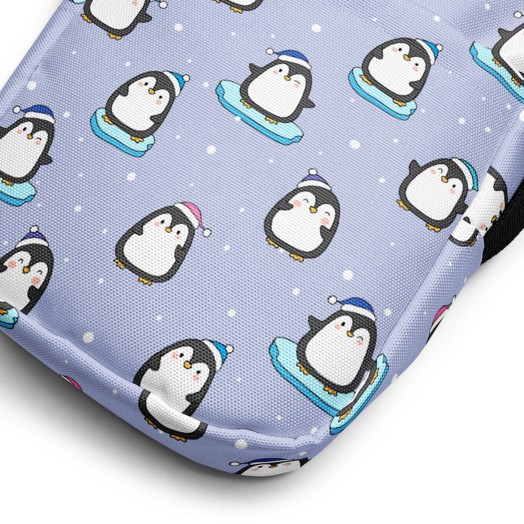 Light purple fabric crossbody purse with cute winter penguins wearing hats and riding sleds pattern