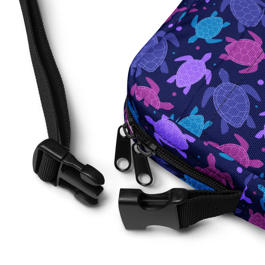 A navy blue fabric girls crossbody purse with a vibrant purple and teal sea turtle pattern