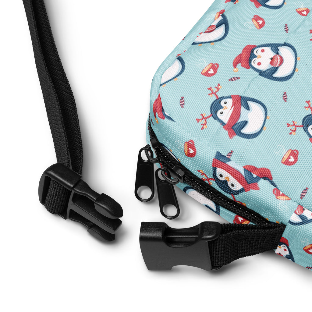 Girls reindeer penguin crossbody purse in light blue with cartoon penguins wearing red hats and black adjustable straps