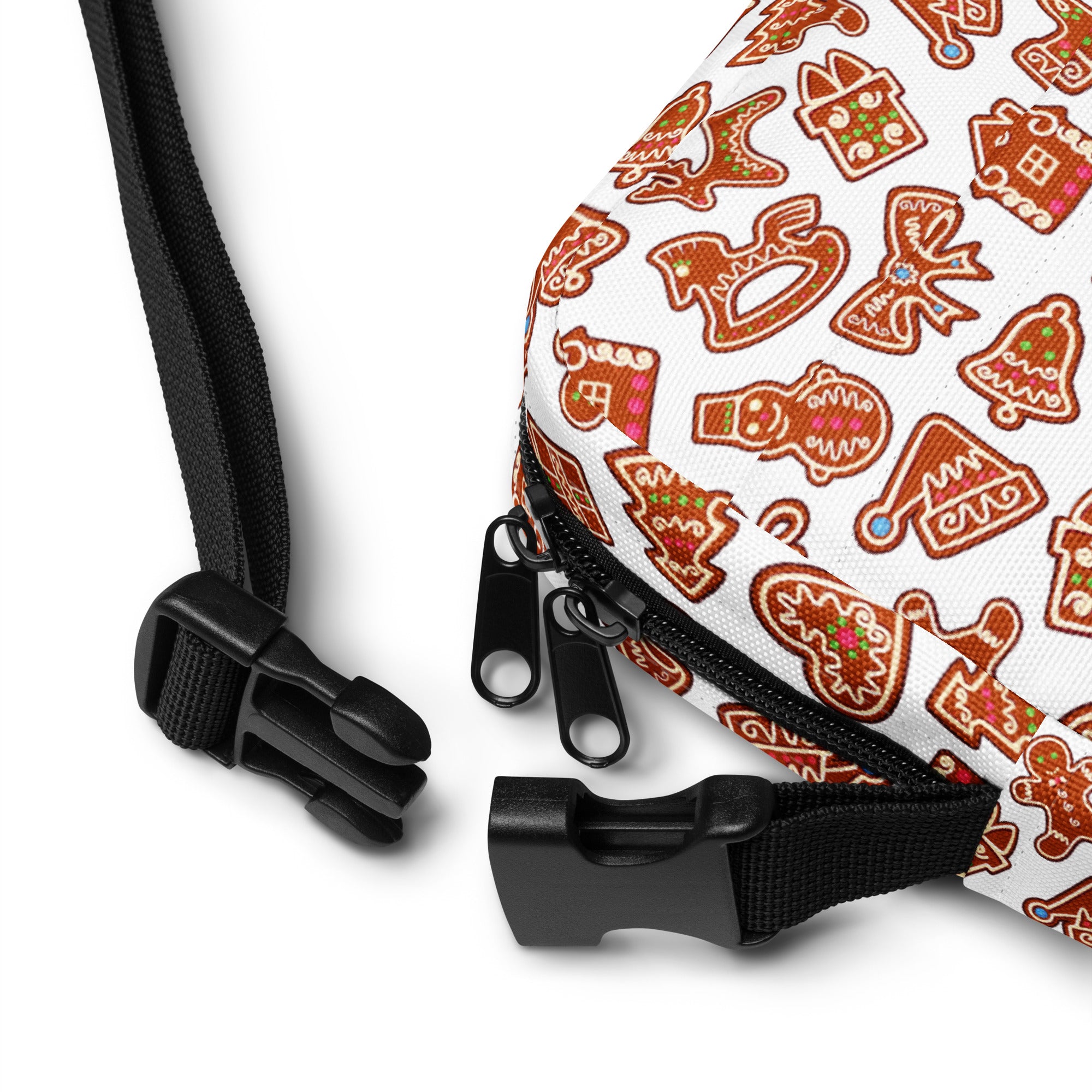 White canvas crossbody bag with festive gingerbread cookie pattern in brown red and green with black straps and zipper pulls