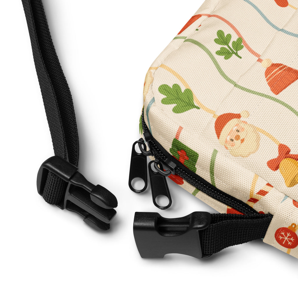 Beige canvas crossbody bag with festive holiday print of cartoon santa ornaments and leaves on cream background