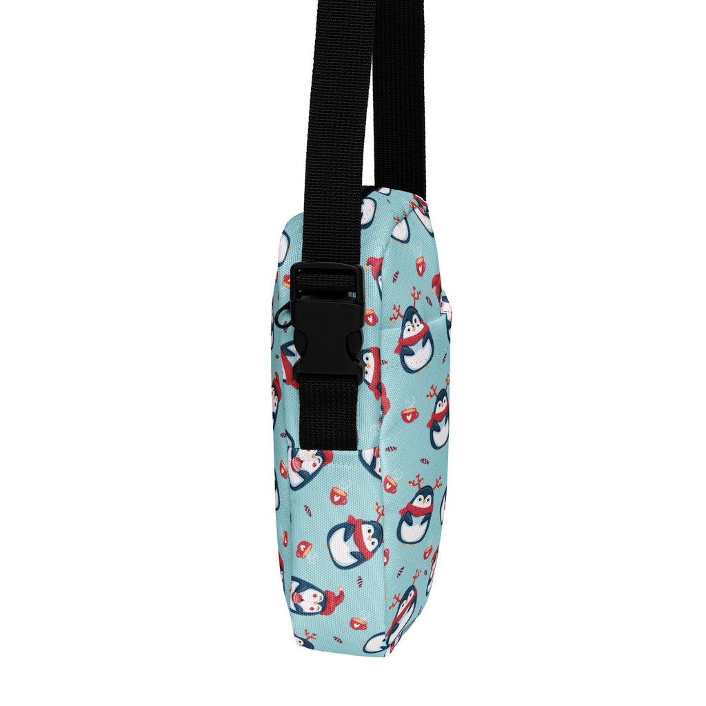 A light blue girls reindeer penguin crossbody purse with cartoon penguins, red scarves, hearts, and candy canes pattern