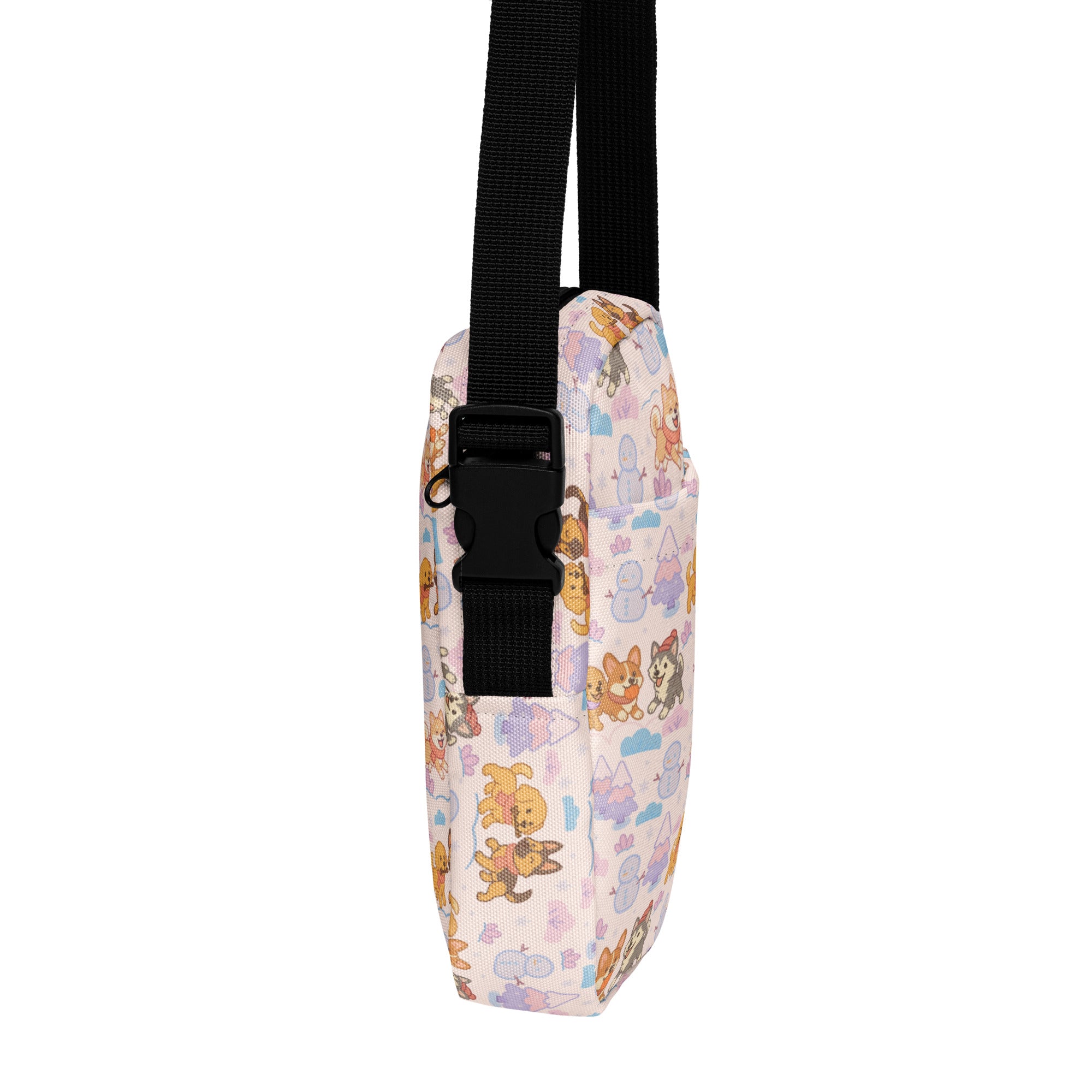 A pastel pink crossbody purse with cartoon dogs and snowmen pattern and black straps for women