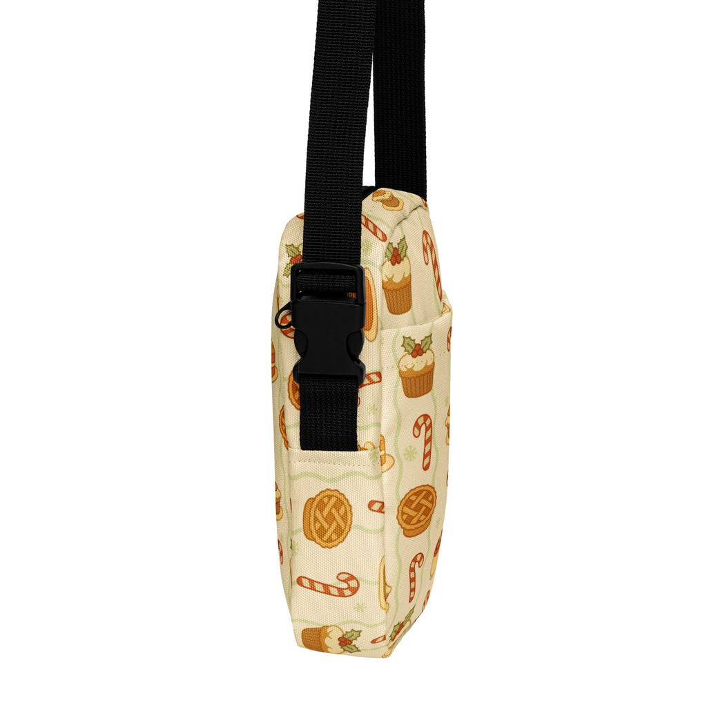 A beige crossbody bag with a festive holiday cupcake candy cane and pie slice pattern in warm orange and brown tones