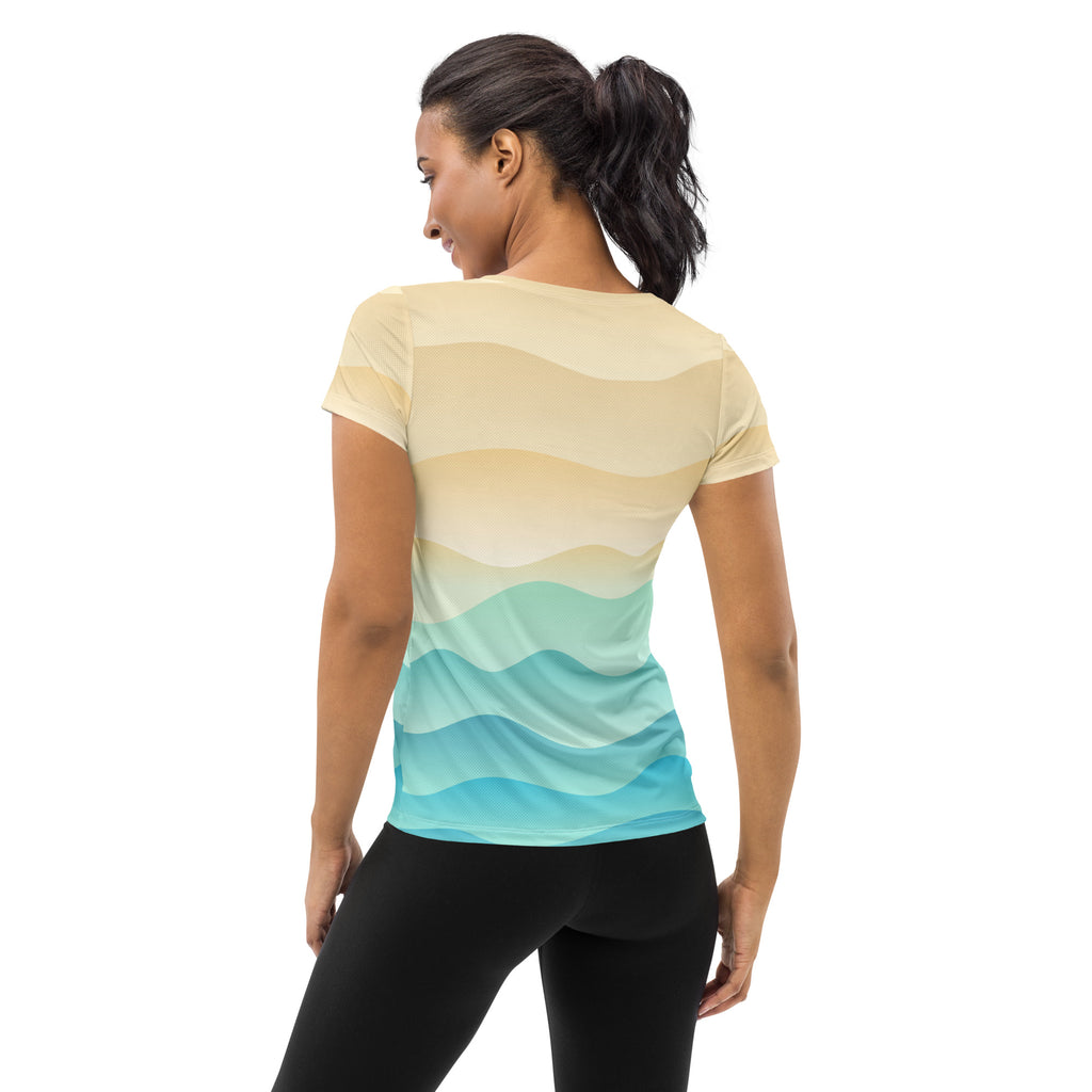 A woman wears a womens sand and ocean wave performance athletic t shirt with smooth yellow to turquoise stripes