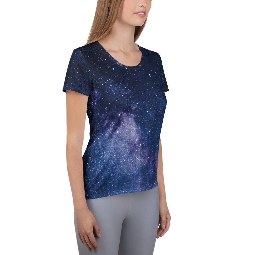 A navy blue women’s short-sleeved galaxy performance t-shirt with purple and white stars, lightweight and moisture wicking