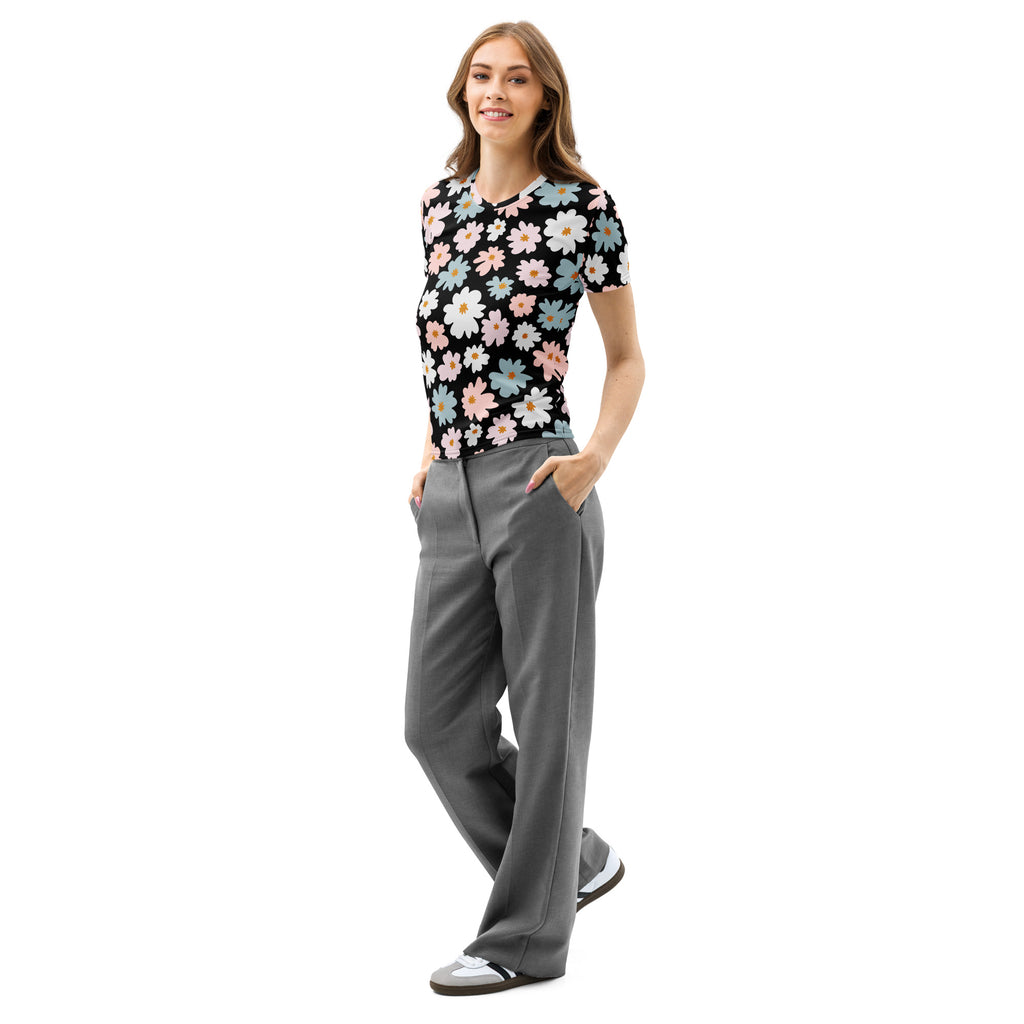 A woman wearing a black cotton women’s retro floral t-shirt with pastel daisies and gray wide-leg trousers
