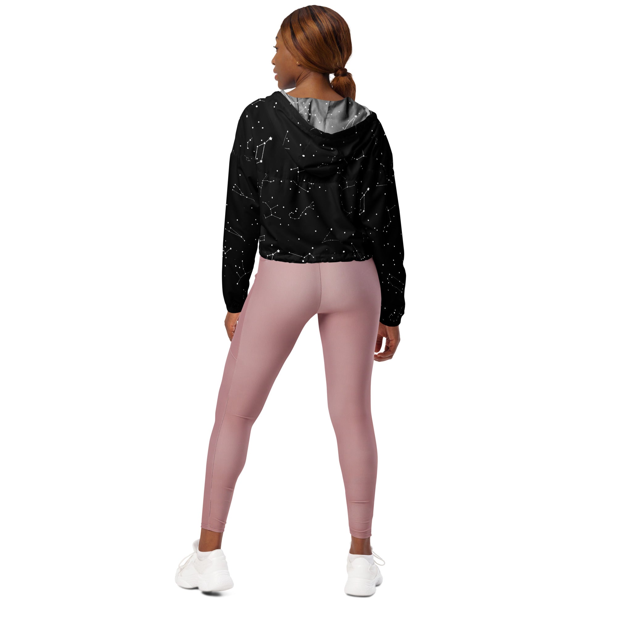 Women’s black cropped hoodie with silver-lined adjustable hood featuring starry constellation print paired with pink leggings