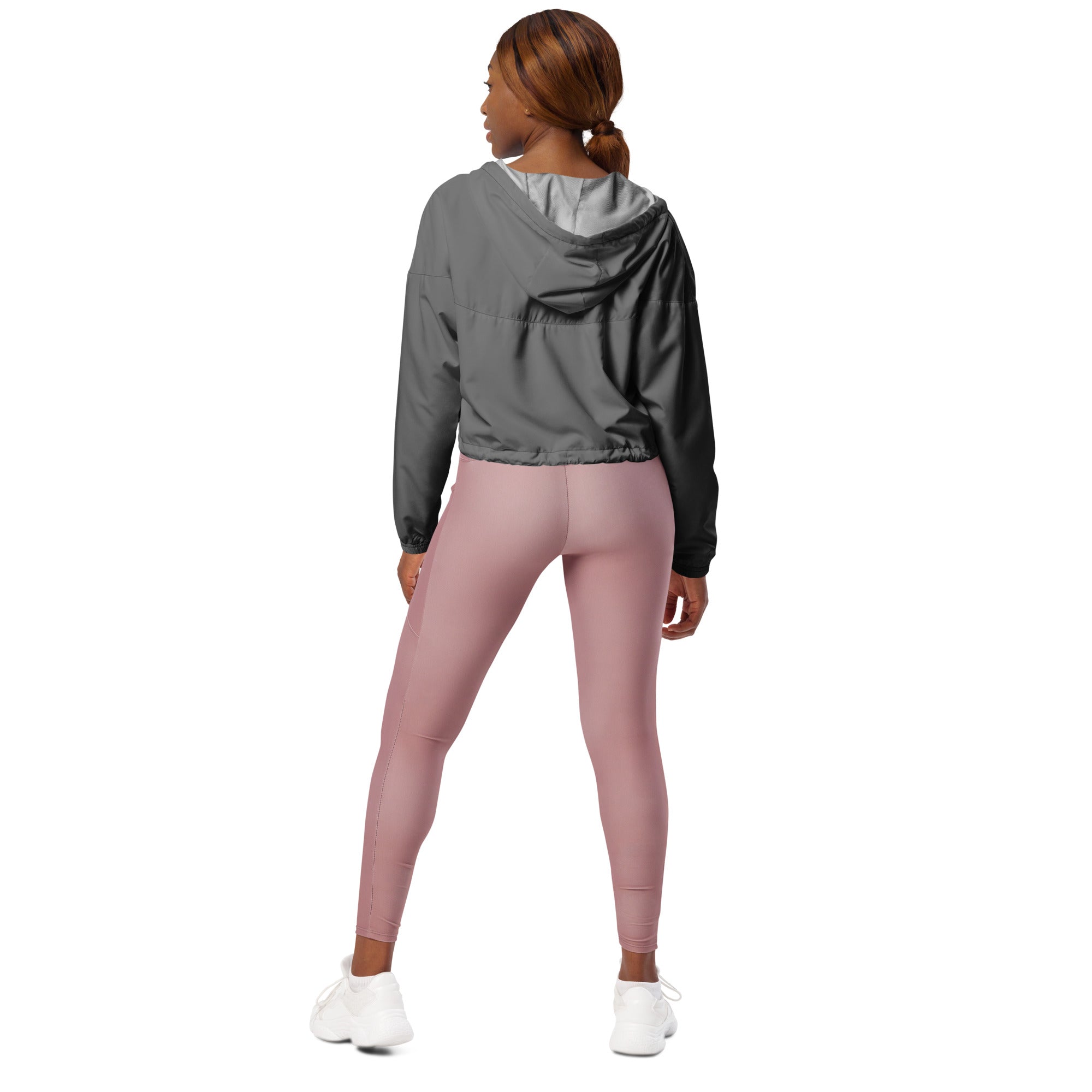 A woman wearing a women’s gray cropped windbreaker with black sleeves lightweight water resistant jacket and pink leggings