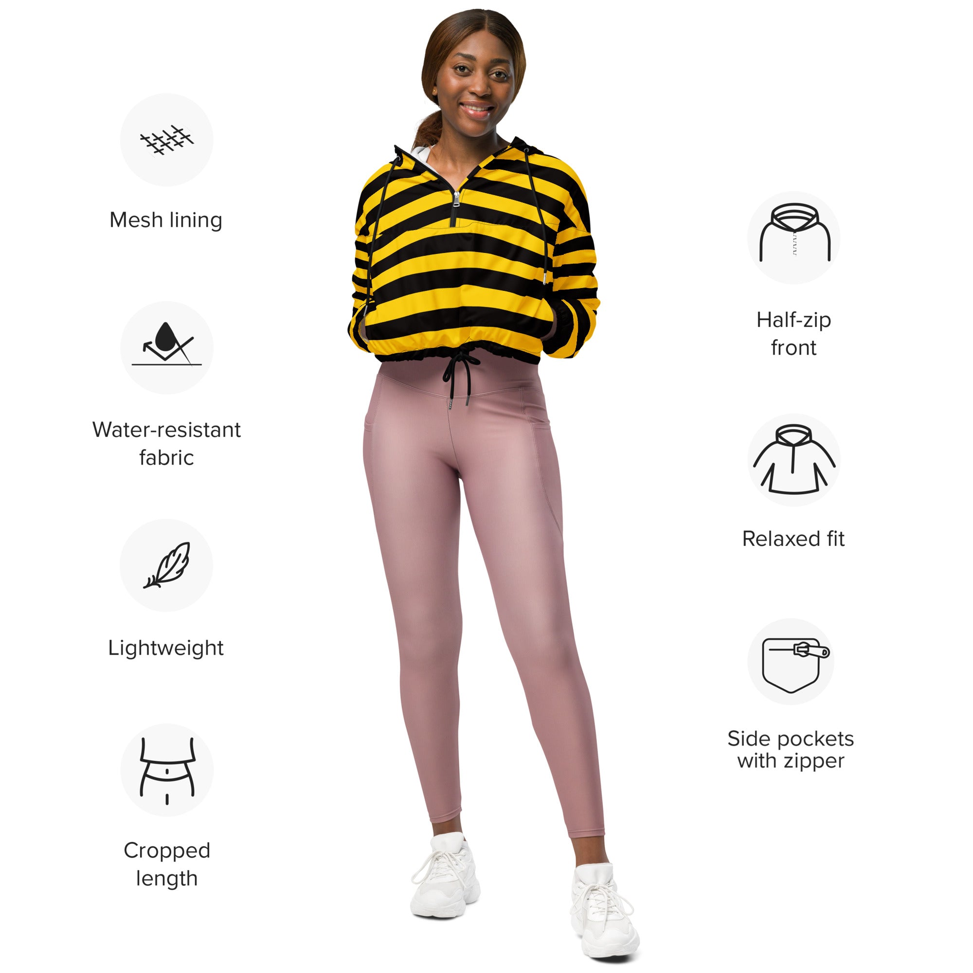 A woman wearing a yellow and black striped cropped windbreaker with mesh lining and zippered pockets