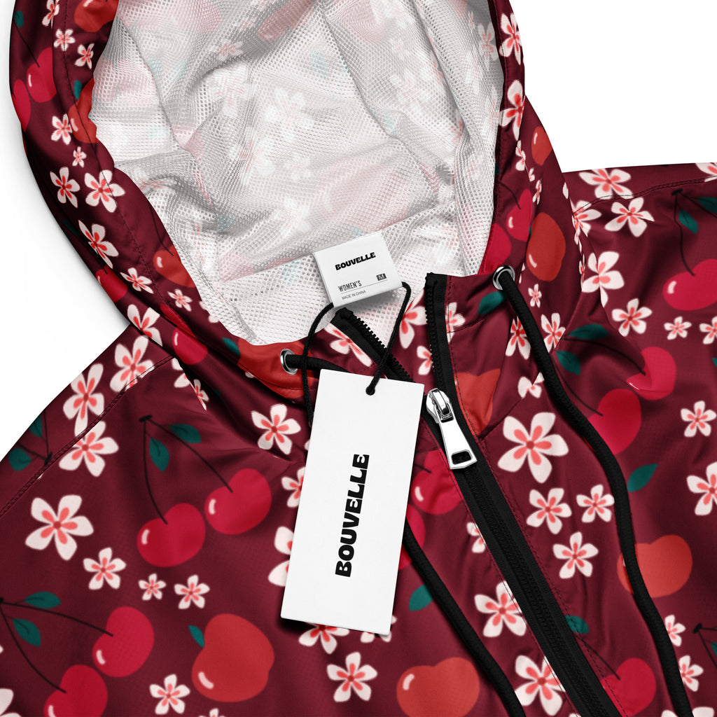 A maroon bouvelle women’s cropped windbreaker with cherry and white flower print, black zipper, and adjustable hood