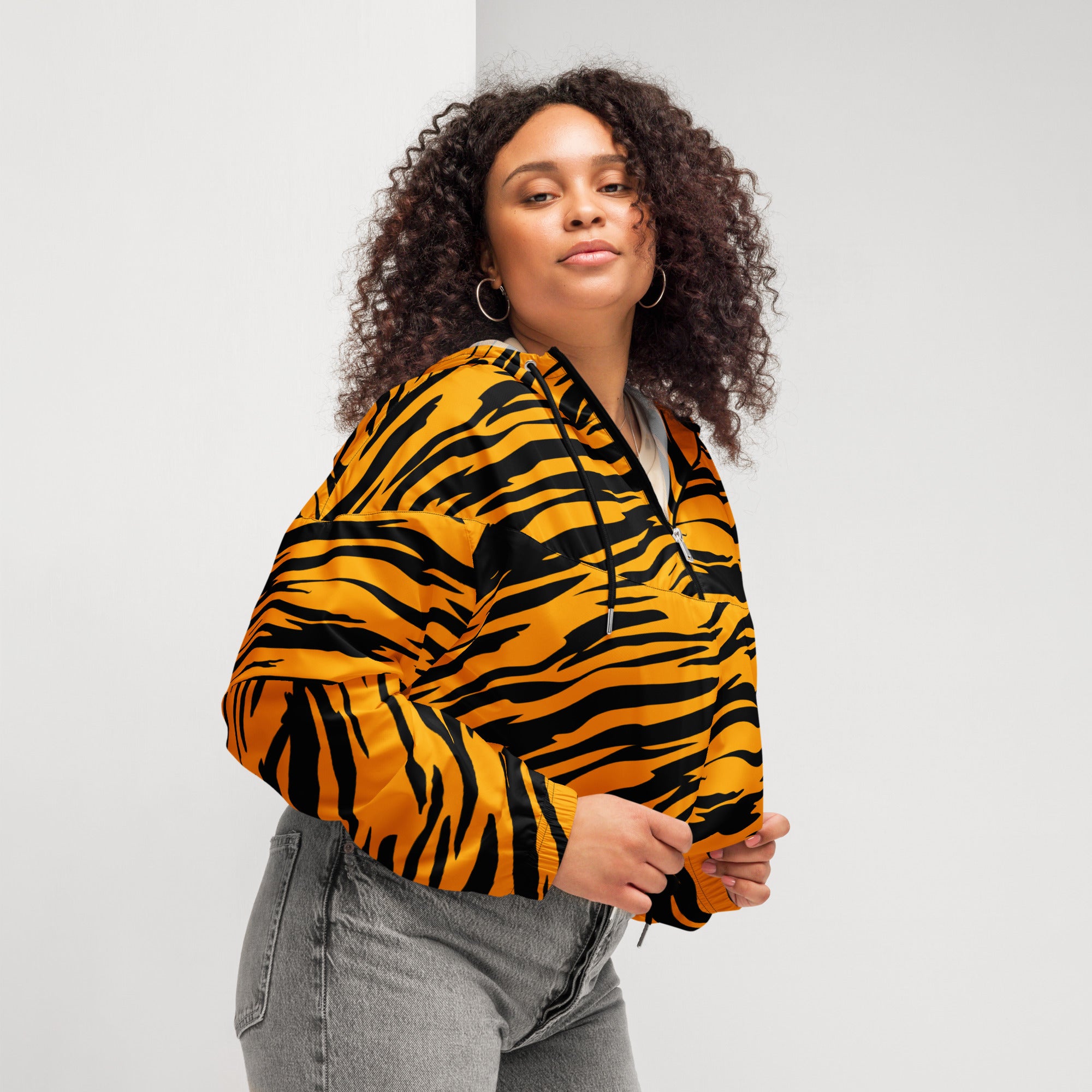 A vibrant orange and black tiger stripe women’s cropped windbreaker with adjustable hood and pockets