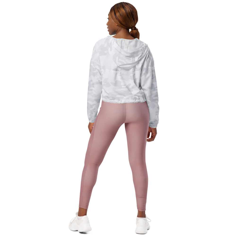 A woman wears a women’s white camouflage cropped windbreaker with adjustable hood and pockets paired with dusty rose leggings