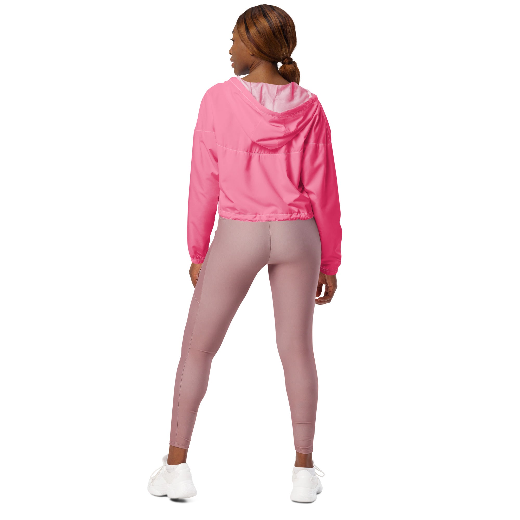 Women’s pink cropped windbreaker lightweight water resistant jacket with adjustable hood worn over mauve leggings