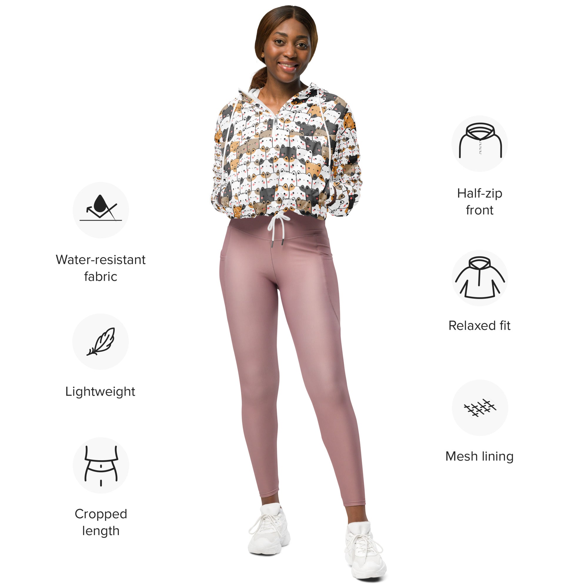 A woman wears a mauve kawaii cat cropped windbreaker with half-zip, adjustable hood, and matching leggings