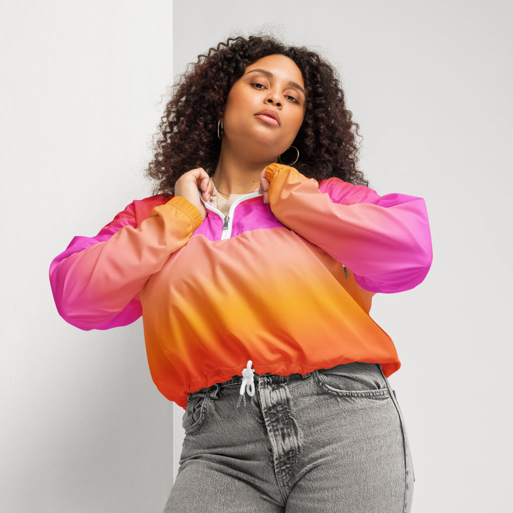 Women’s sunset ombre cropped windbreaker in vibrant pink to orange nylon with white zipper pull and adjustable hood