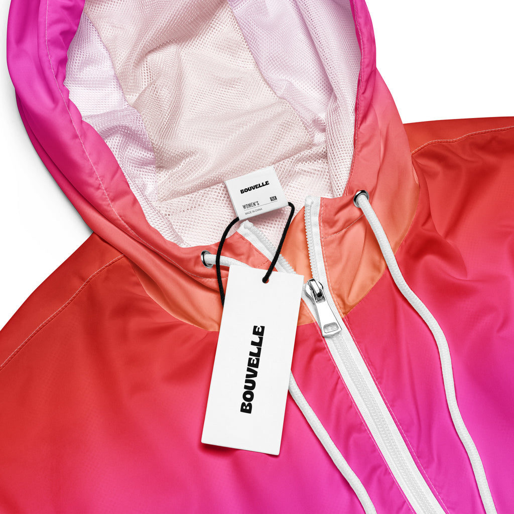 A vibrant gradient pink and orange women’s sunset ombre cropped windbreaker with mesh-lined hood and pockets