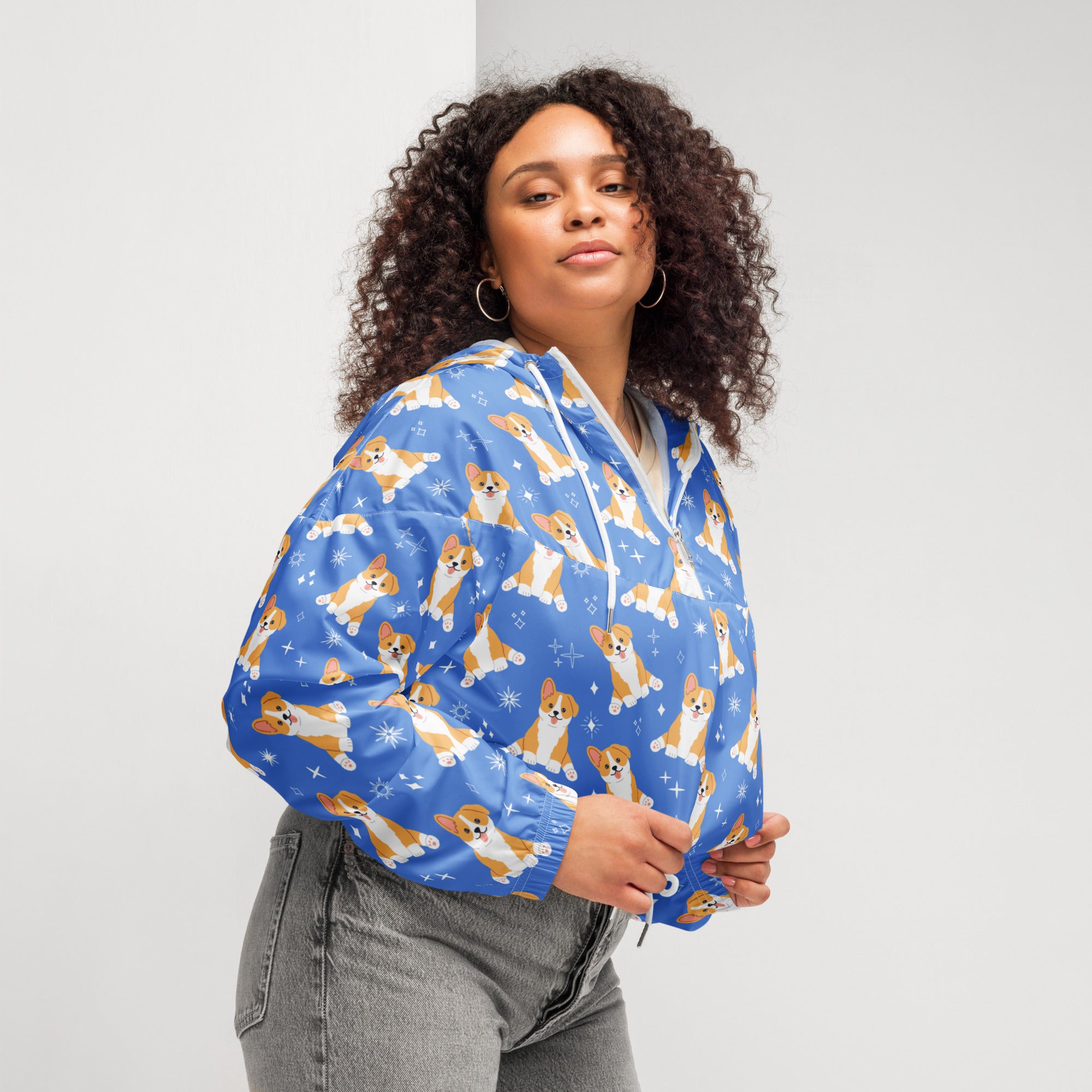 Women’s blue cropped bomber jacket with playful tan and white corgis and snowflake accents, lightweight and water resistant