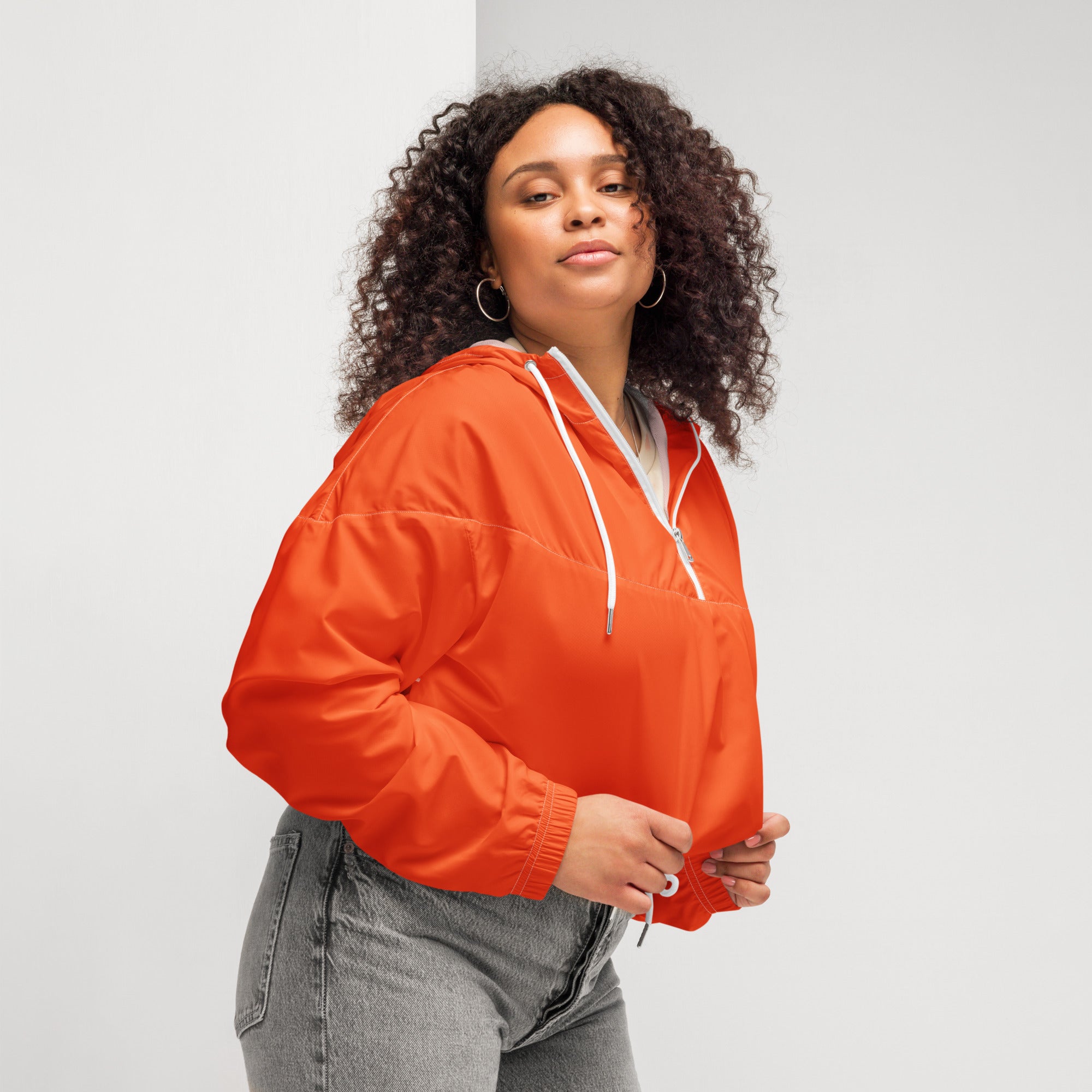 Women’s bright orange nylon cropped windbreaker with white drawstrings zipper accents and adjustable hood
