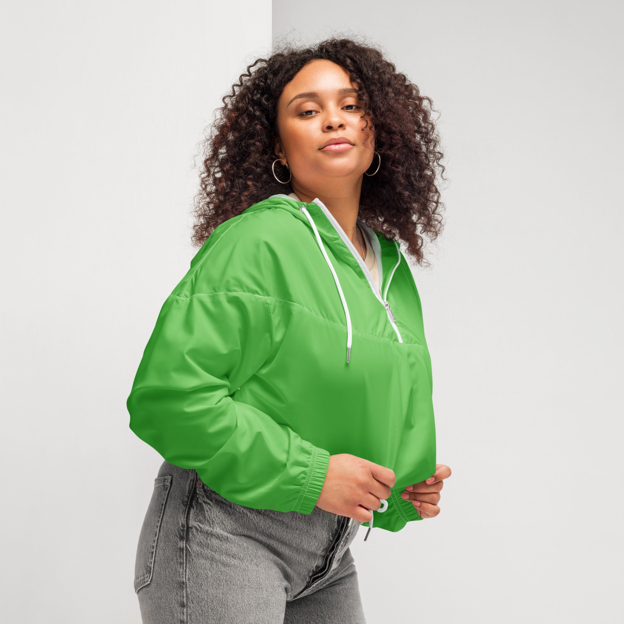Women’s bright green cropped windbreaker made of lightweight nylon with white drawstrings and zipper accents