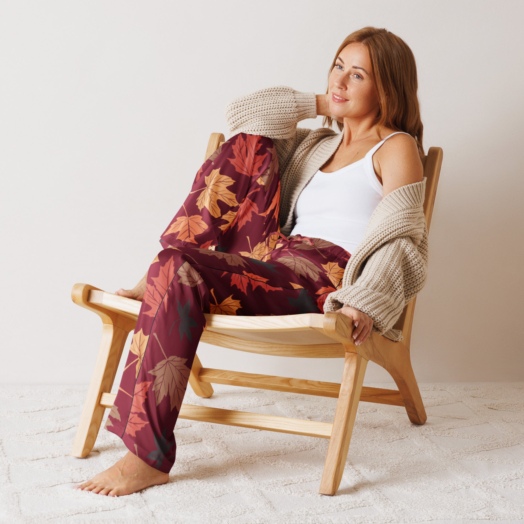 Woman wearing lightweight maroon women’s autumn leaves pajama pants with drawstring waist and beige knitted cardigan