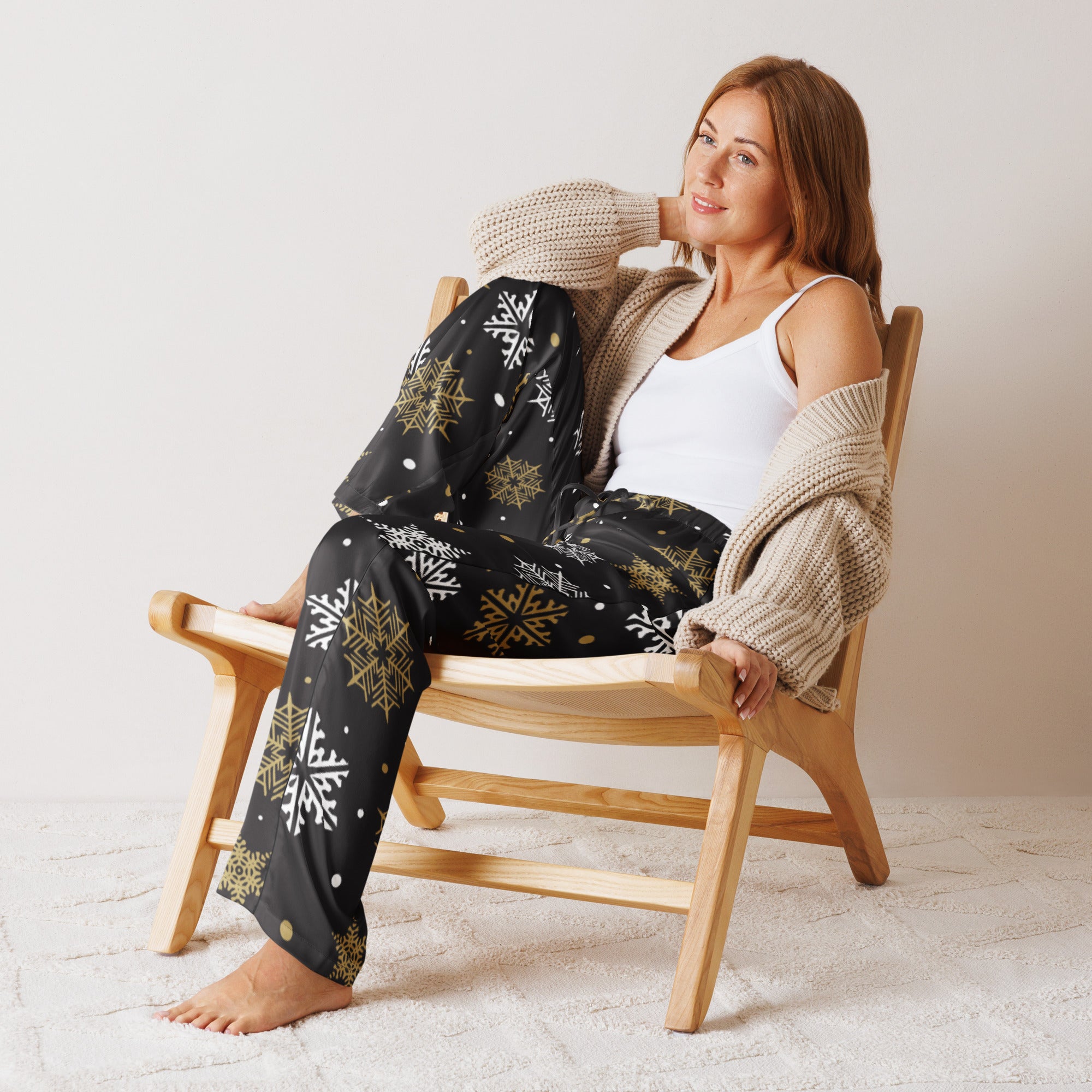 Women’s black pajama pants with white and gold snowflakes lightweight relaxed fit worn with beige knit cardigan