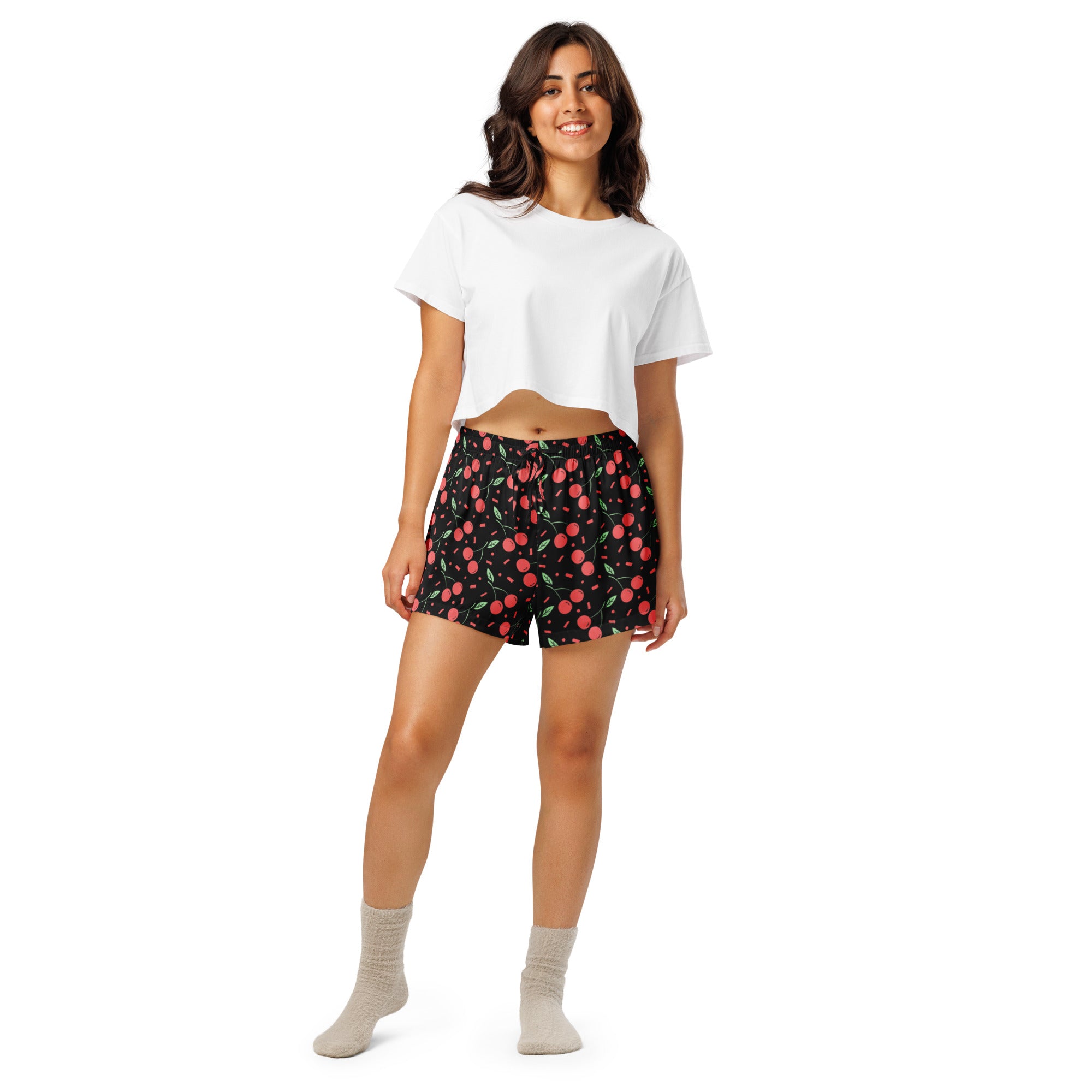 Women’s black cherry confetti silky pajama shorts with vibrant red cherry pattern worn with white crop top