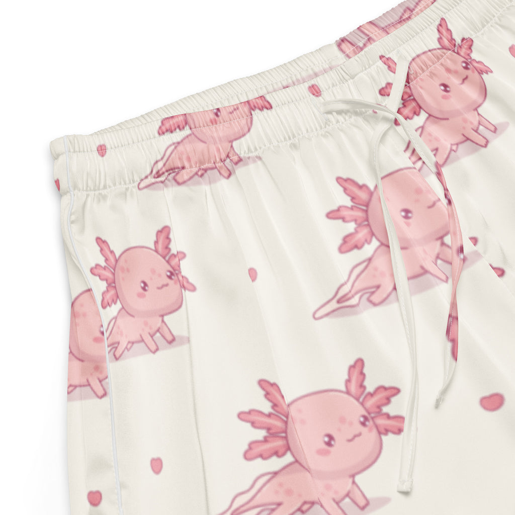 Cream-colored silky pajama pants with pink axolotl and heart patterns featuring a relaxed fit and drawstring waist