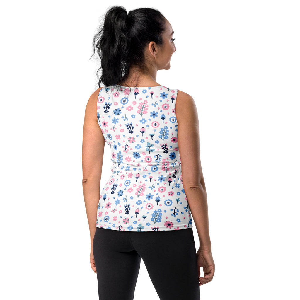 A white sleeveless peplum tank top with pink and blue floral and peace sign patterns in quick drying, buttery soft fabric with UPF 50+