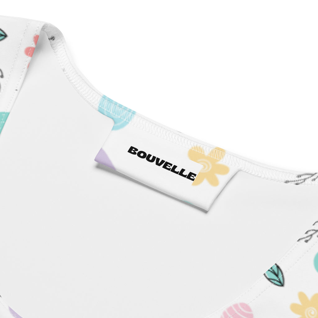 White fabric tag with black bouvelle branding and yellow flower on women’s pastel chick easter quick drying tank top