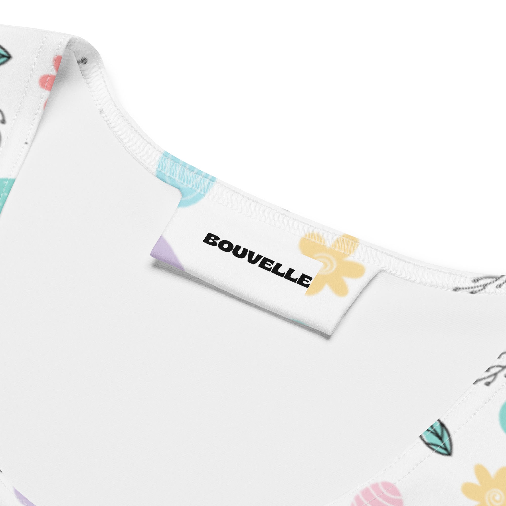 White fabric tag with black bouvelle branding and yellow flower on women’s pastel chick easter quick drying tank top
