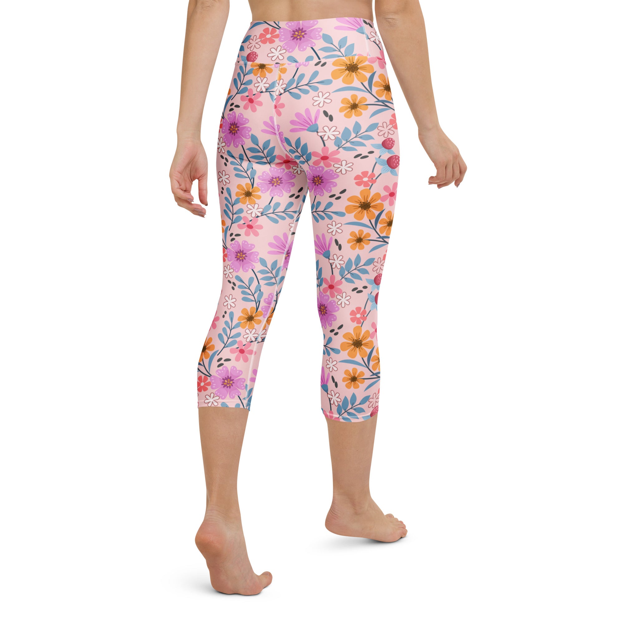Women’s pink floral buttery soft high-rise yoga capri leggings with purple orange white flower pattern on light pink background