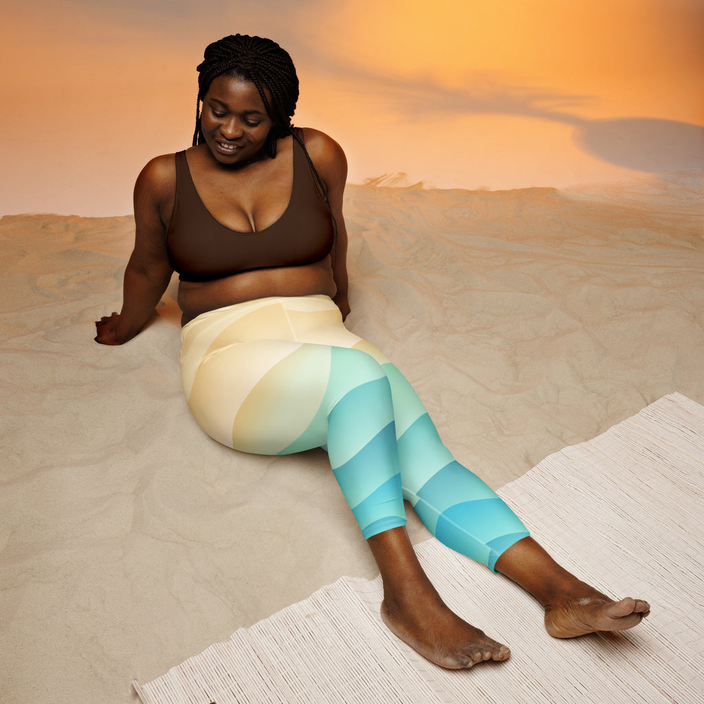A woman wearing brown sports bra and coastal gradient blue to cream striped buttery soft yoga capri leggings