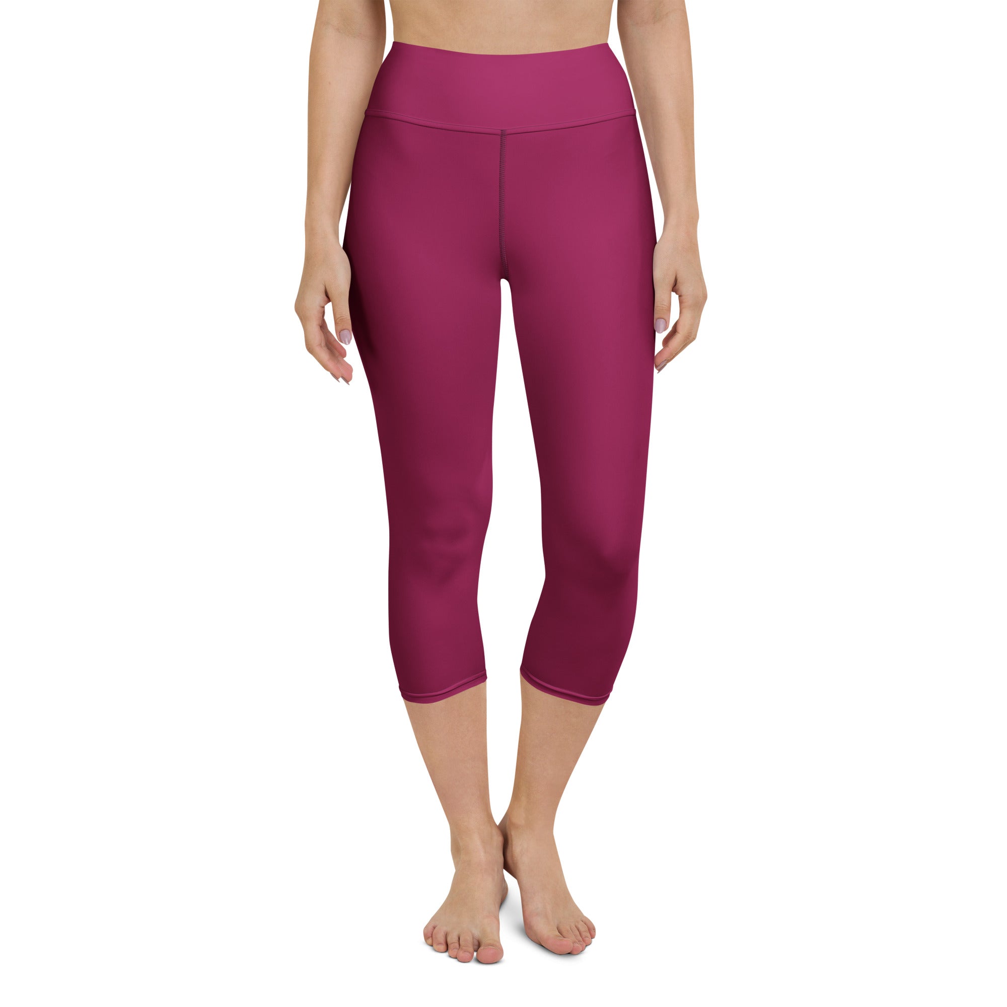 A pair of high-waisted solid magenta buttery soft yoga capri leggings made from moisture-wicking stretch fabric