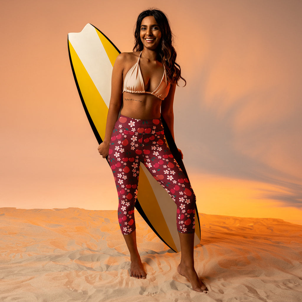 Woman wearing high-rise buttery soft yoga capri leggings with pink cherry blossom and polka dot patterns on dark red base
